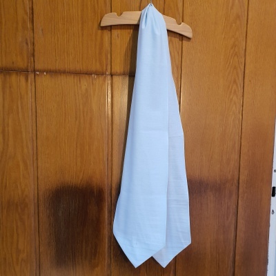 Pano branco pendurado num cabide de madeira contra porta de madeira.