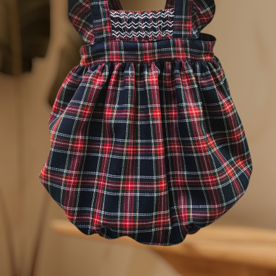 Vestido de bebé xadrez vermelho e preto com folhos alças pendurado em cabide.