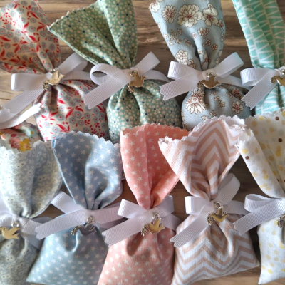 Sacos de tecido coloridos com padrões variados e laços brancos com pendentes de pássaros.