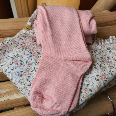 Meias cor-de-rosa sobre roupa floral e madeira