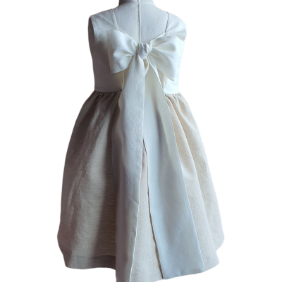 Vestido de criança bege e branco com laço grande nas costas, mostrado num manequim