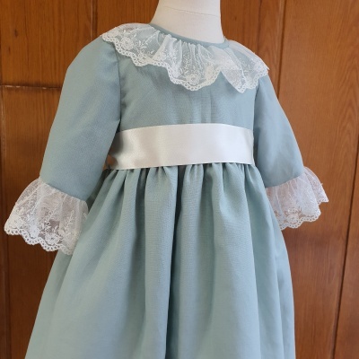 Vestido infantil azul claro com renda branca e faixa branca na cintura