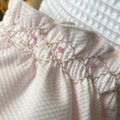 Peça de roupa branca com bordado rosa e bege em padrão circular