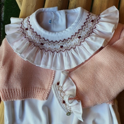 Conjunto de roupa bebê com camisola de malha rosa e body branco com gola bordada.