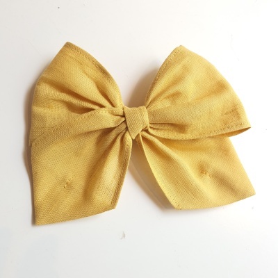 Laço amarelo mostarda em tecido sobre fundo branco