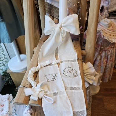 Laço branco de tecido com bordados e fita elástica em suporte de madeira