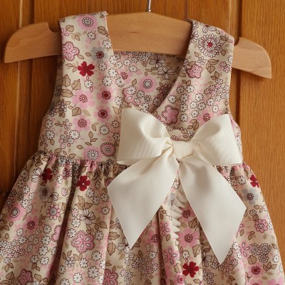 Vestido infantil floral com laço branco em cabide de madeira