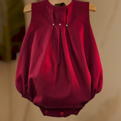 Body de bebé vermelho escuro pendurado num cabide de madeira