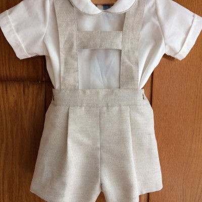 Conjunto infantil com camisa branca e calção bege com suspensórios