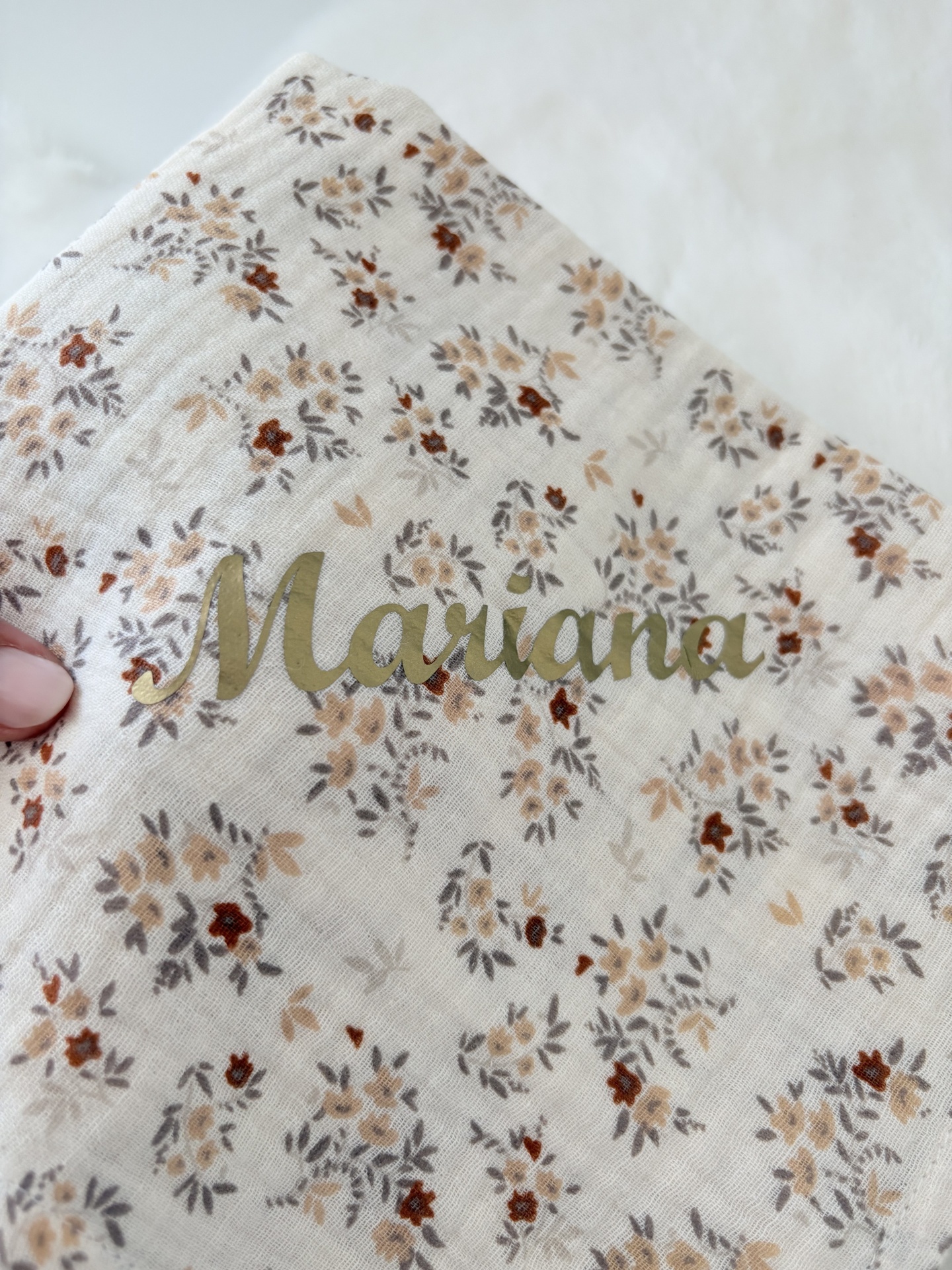 Fralda musselina flores de outono com nome Mariana Pano branco com padrão floral castanho e bege e nome Mariana em letras douradas