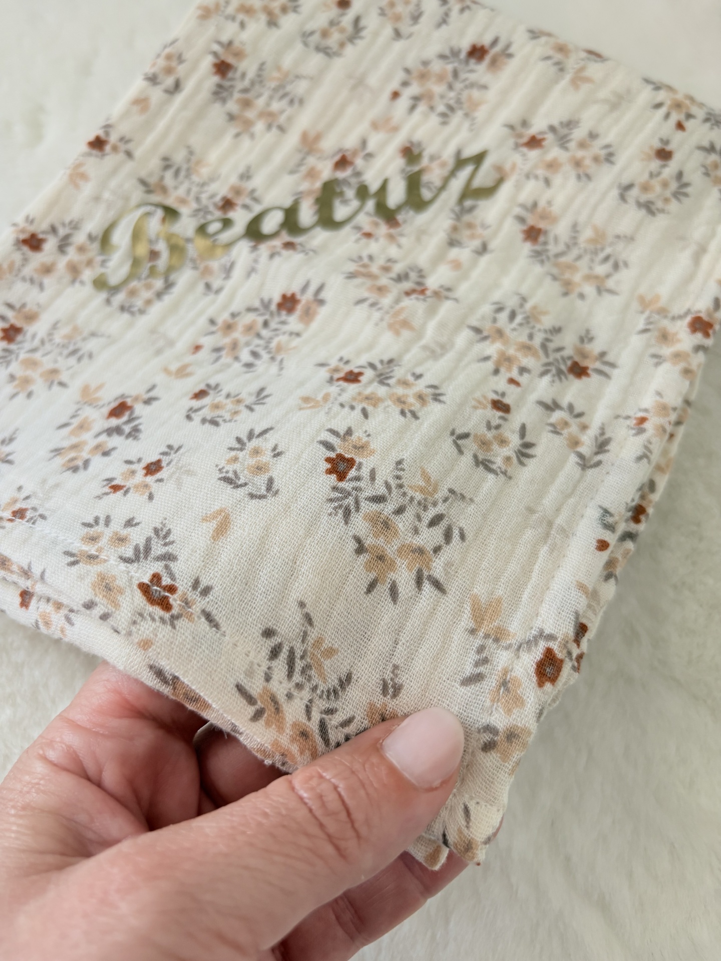Fralda musselina flores de outono com nome Beatriz Tecido branco com padrão floral castanho e cinza e texto verde Beatruz