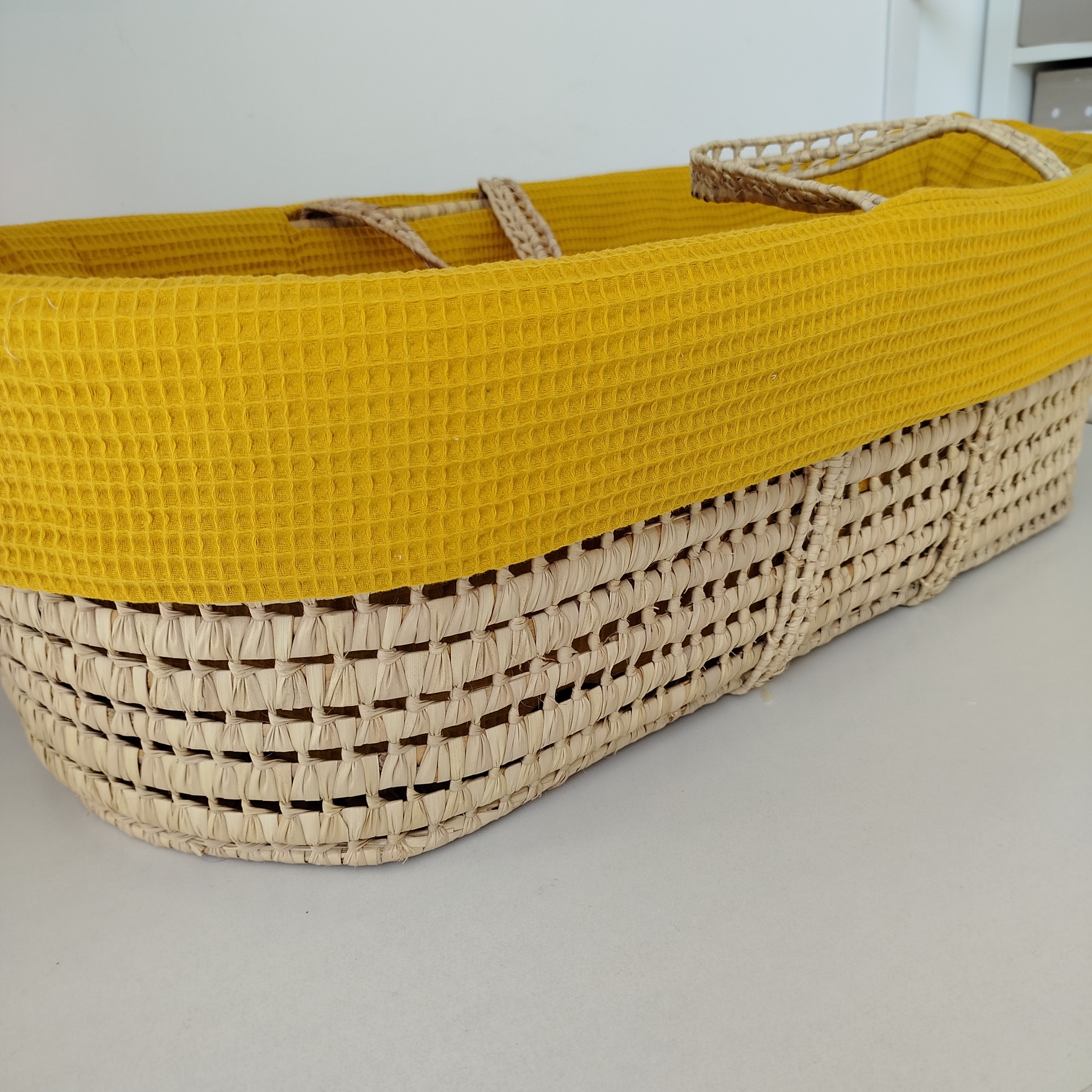 Forra para alcofa | alcofa de verga | berço bebé | waffle mostarda Cesto de vime com tecido amarelo na borda sobre superfície branca