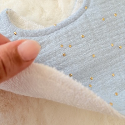 Babete infantil azul claro com pontos dourados e interior felpudo branco