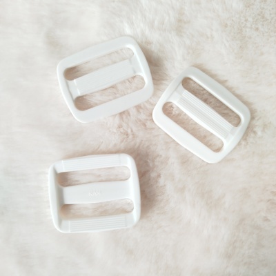 Três fivelas retangulares brancas sobre superfície peluda creme