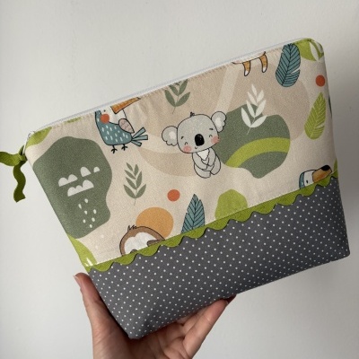 Bolsa de tecido com padrão de animais e folhas junto a uma mão