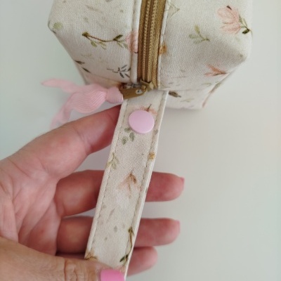 Bolsa pequena quadrada bege com flores em tons pastel e alça com botão rosa