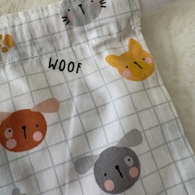 Tecido branco com padrão de quadrícula cinza claro e desenhos de caras de cães coloridos