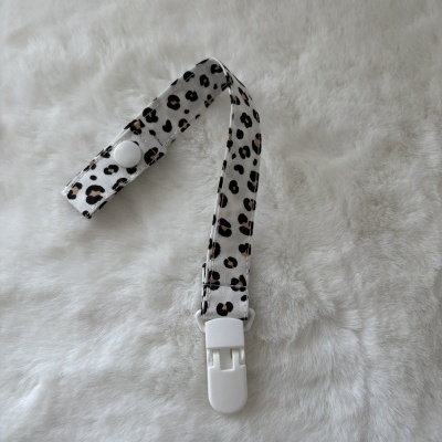 mola com padrão animal print e clip branco sobre superfície felpuda branca