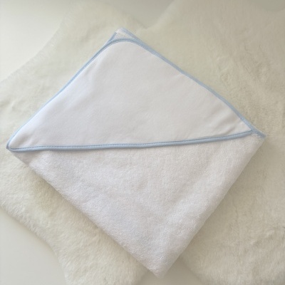 Toalha branca para bebé com capuz bordado azul clara sobre superfície felpuda branca