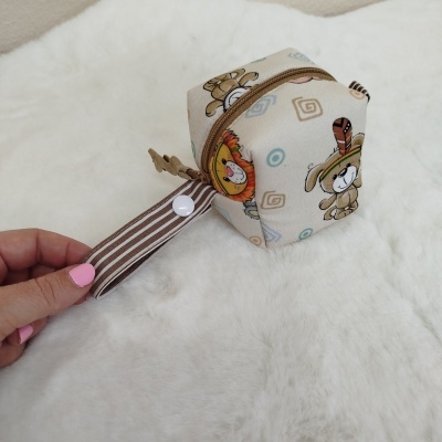 Bolsa pequena em tecido bege com padrão de animais cartoon e fecho castanho
