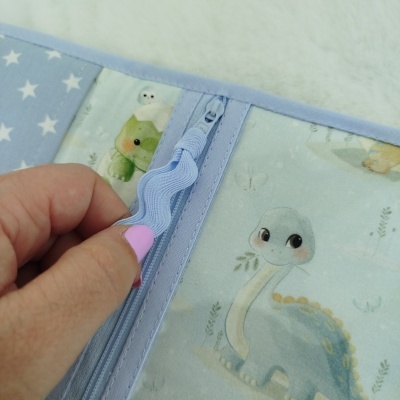 Produto tecido com padrão infantil de dinossauro azul claro com fecho de correr azul