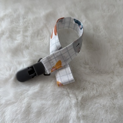 Prendedor de chupeta em tecido branco com padrão de grelha cinzenta e clip preto