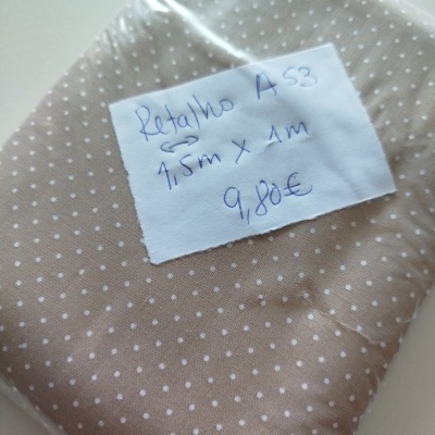 Tecido bege com pontos brancos embalado em plástico com etiqueta manuscrita