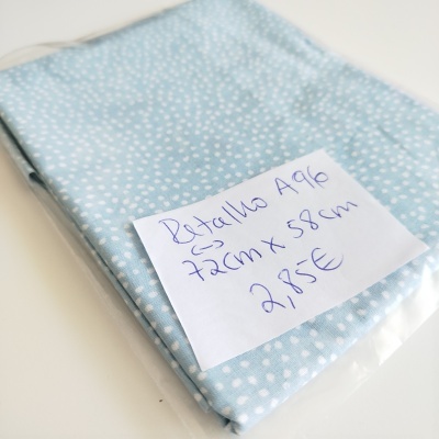 Retalho de tecido azul claro com pontos brancos e etiqueta manuscrita