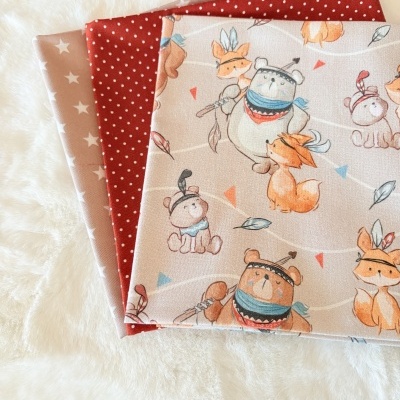 Tecidos com padrões de estrelas, pontos e animais sobre fundo branco felpudo.