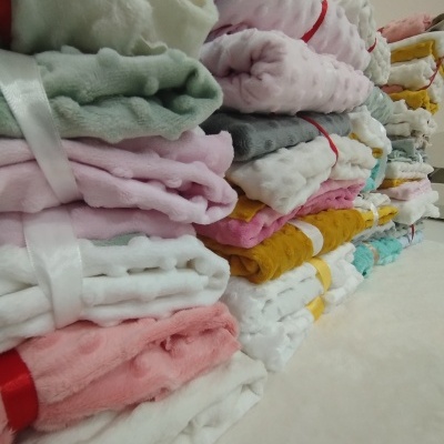 Mantinhas felpudas coloridas empilhadas com fitas de cetim em superfície clara