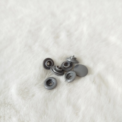 Botões de pressão cinza sobre superfície felpuda branca