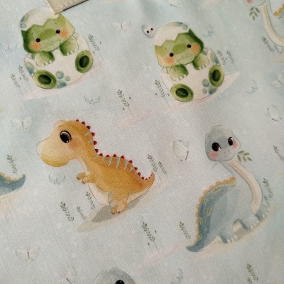 Tecido com padrão de dinossauros em cores pastel e etiqueta com texto