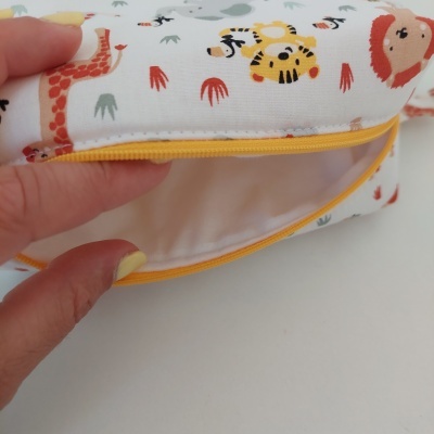 Bolsa ou estojo com estampado infantil de animais sobre fundo branco e fecho amarelo.