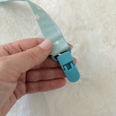 Fita azul clara com estrelas brancas e clip azul na mão sobre fundo branco felpudo