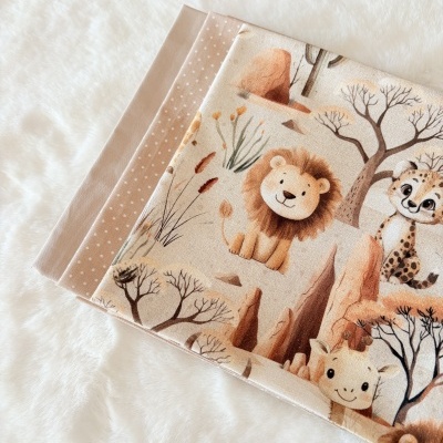 Tecidos dobrados com padrões de animais da selva e cores neutras.