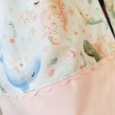 Tecido infantil com animais marinhos e padrão floral sobre fundo azul e cor-de-rosa.