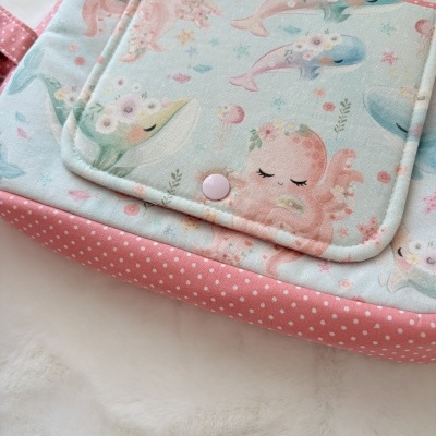 Bolsa de tecido com padrão de animais marinhos e detalhe rosa com bolinhas brancas.