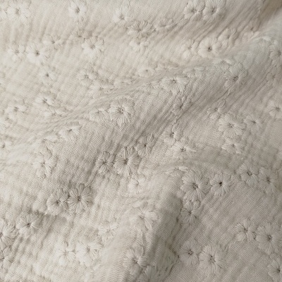 Tecido branco com bordados de flores pequenas em relevo