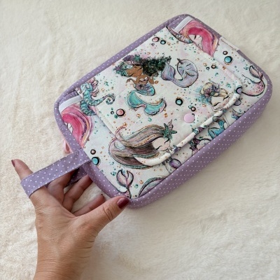 Mala ou carteira com padrão de sereias coloridas e bordas lilás com bolinhas brancas