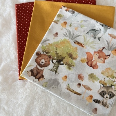 Três tecidos de algodão com padrões diferentes colocados sobre superfície branca felpuda.