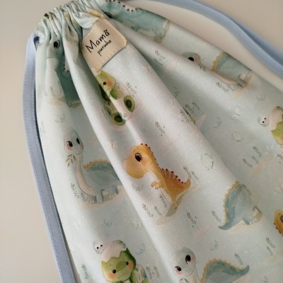 Saco de tecido com estampa de dinossauros coloridos e etiqueta 'Mamã presente'.