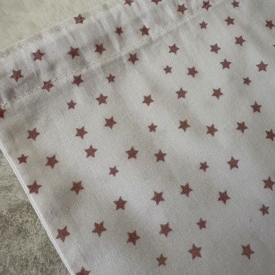 Tecido branco com estrelas castanhas e costura visível