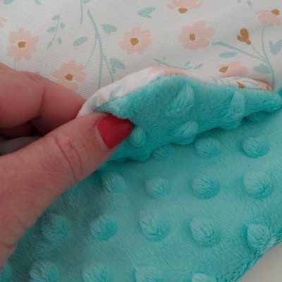 Tecido estampado com flores cor-de-rosa e azul com textura aveludada azul turquesa e bolinhas em relevo