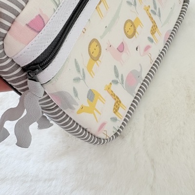 Bolsa para bebé com padrão de animais coloridos e alças às riscas.