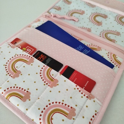 Carteira de tecido rosa com padrão de arco-íris e cartões inseridos