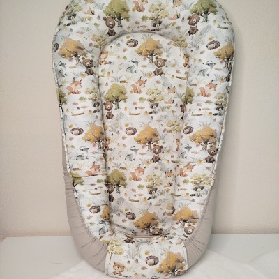 Ninho para bebé com padrão de animais da floresta em fundo branco e bordas cinza