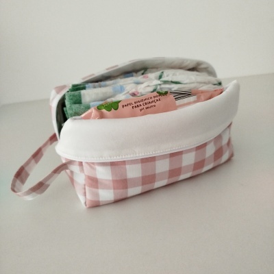 Necessaire rosa com padrão xadrez branco e panos de papel dentro
