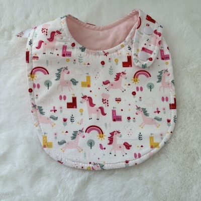 Babete de bebé rosa com estampado de unicórnios e castelos
