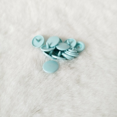 Botões de plástico azul claro sobre tecido branco