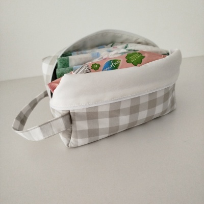 Bolsa xadrez bege e branco aberta com pacotes coloridos no interior
